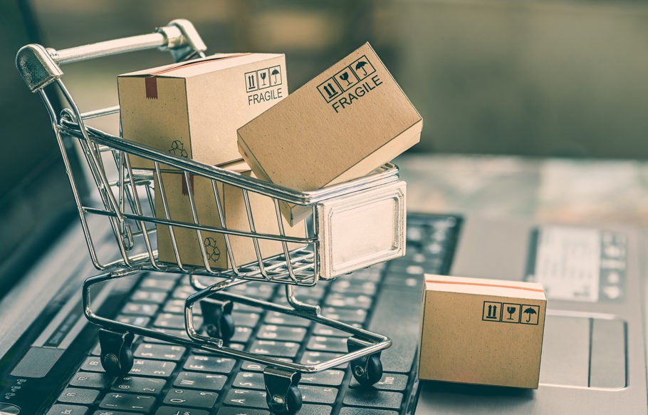 Miniature shopping cart with boxes on a laptop