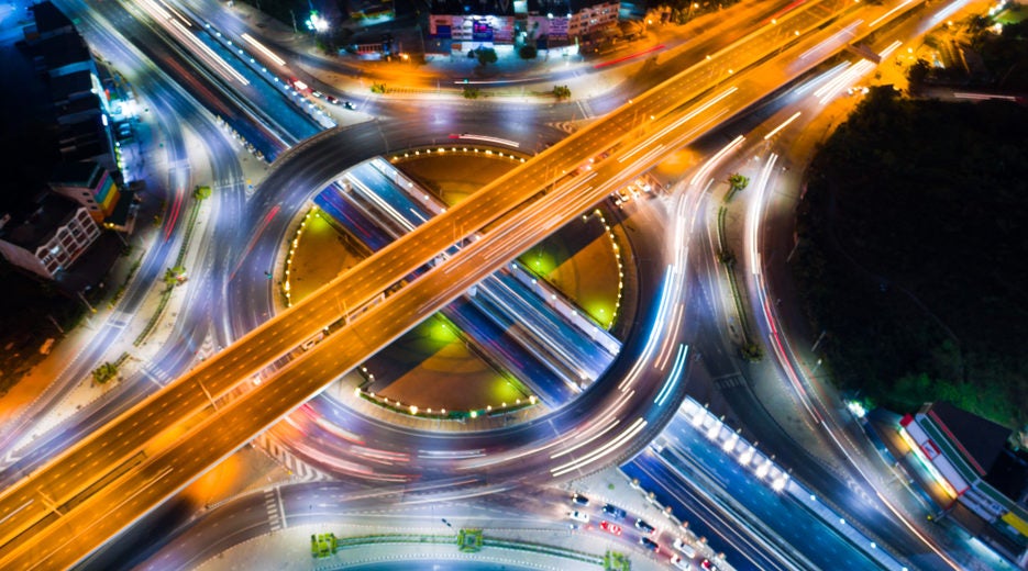 Roundabout intersection city road at night with vehicle light movement aerial view