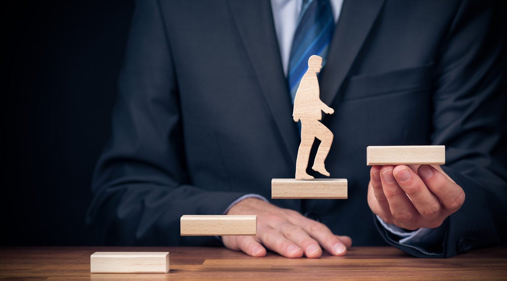 Man in business suit holding floating stairs, cutout of man walking up stairs