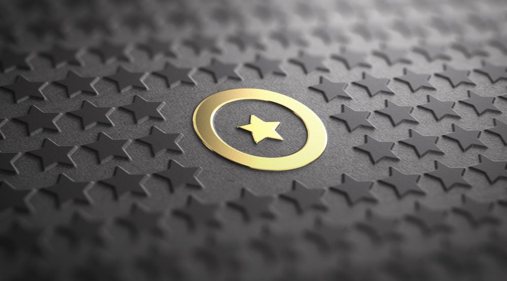 Many stars in relief on black paper background with focus on a golden one surrounded by a circle. Concept of Uniqueness and quality difference. 3D illustration