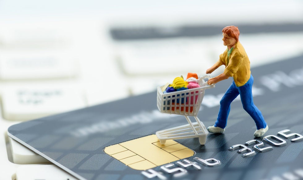 Miniature figurine : a shopper pushes a shopping cart on a smart credit card and a keyboard. Concept of brick and mortar stores nowadays face with increased competition from internet online ecommerce.