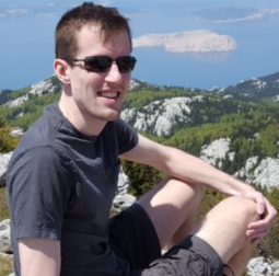 Picture of Seth Duda, sitting on rock above mountain lake