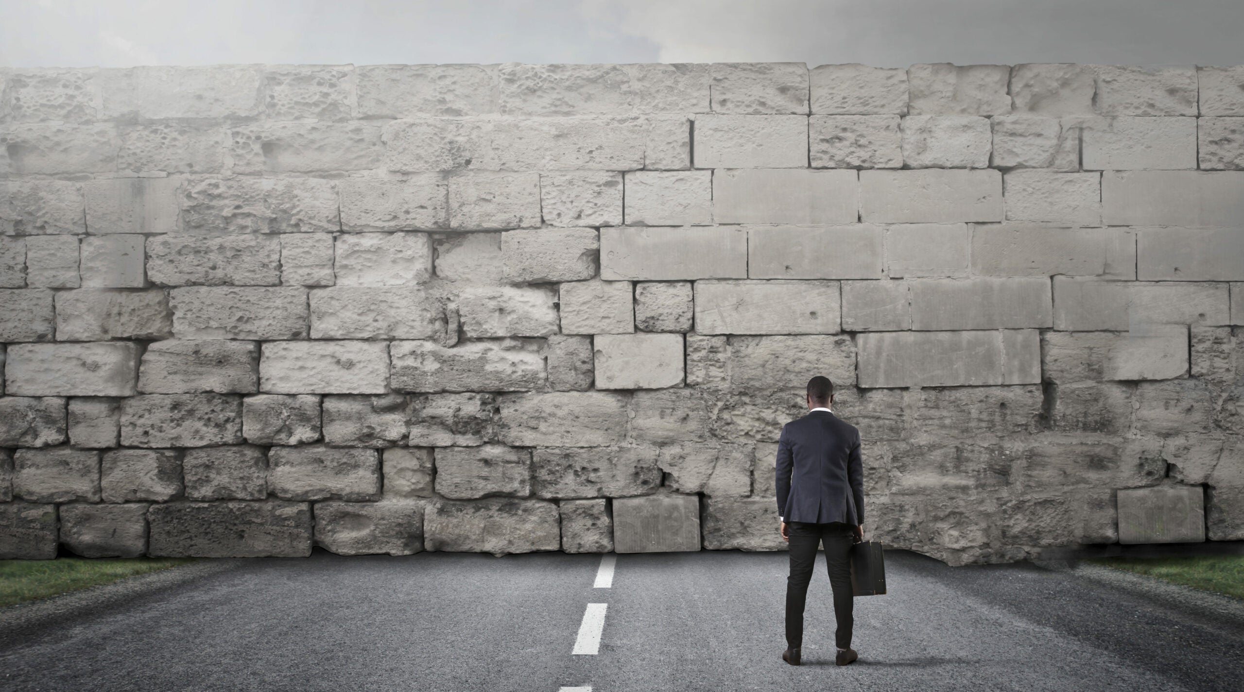 Businessman facing a big stone wall