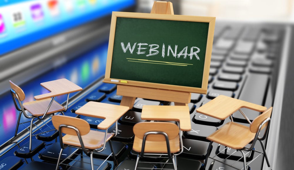 Minature school desk and "Webinar" chalkboard on laptop computer