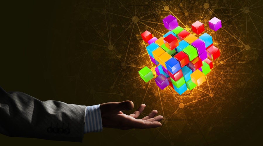 Close-up of businessman hand holding cube figure as symbol of innovation. 3D rendering.